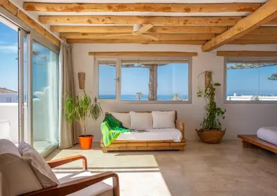 a living room with a couch and windows at Exotic Beachfront Retreat Handcrafted Bohemian Luxury in Cádiz