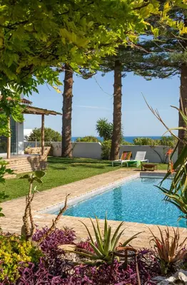 a swimming pool in a yard with trees at Exotic Beachfront Retreat Handcrafted Bohemian Luxury in Cádiz