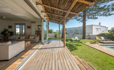 a backyard with a wooden deck and a swimming pool at Exotic Beachfront Retreat Handcrafted Bohemian Luxury in Cádiz