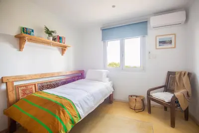 a bedroom with a bed and a chair and a window at Exotic Beachfront Retreat Handcrafted Bohemian Luxury in Cádiz