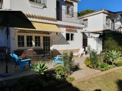 a patio with two blue chairs and an umbrella at La casa bianca in Novo Sancti Petri