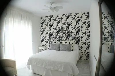 a bedroom with a bed with a black and white wallpaper at Vive Sanlúcar con aparcamiento en la puerta in Sanlúcar de Barrameda