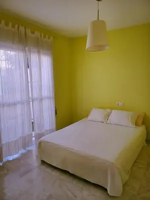 a bedroom with a large white bed and a window at Vive Sanlúcar con aparcamiento en la puerta in Sanlúcar de Barrameda