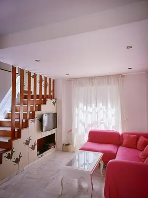 a living room with a red couch and stairs at Vive Sanlúcar con aparcamiento en la puerta in Sanlúcar de Barrameda