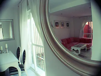 a mirror reflecting a living room with a red couch at Vive Sanlúcar con aparcamiento en la puerta in Sanlúcar de Barrameda