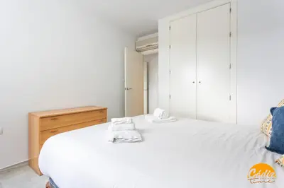 a bedroom with a white bed and a wooden dresser at Retama Golf by Cadiz Time in Novo Sancti Petri