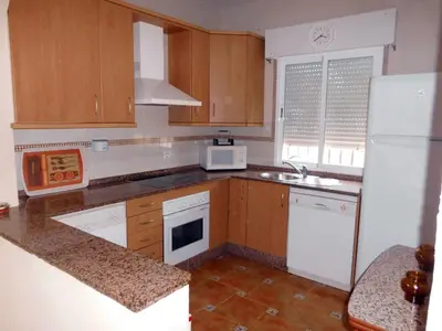 a kitchen with wooden cabinets and a white refrigerator at Librada de las olas in Cádiz