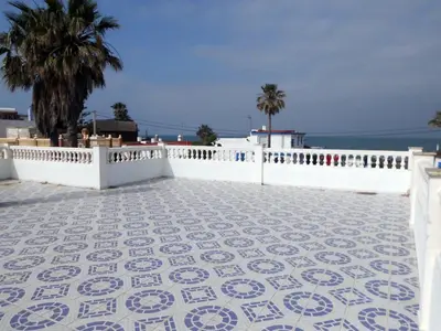 a tile patio with a white fence and palm trees at Librada de las olas in Cádiz