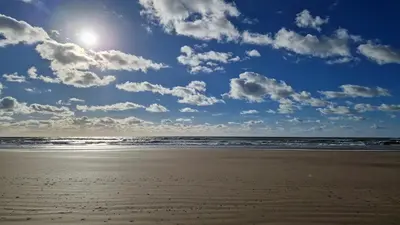 a sandy beach with the ocean and a cloudy sky at Librada de las olas in Cádiz