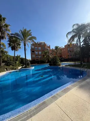 a large swimming pool with palm trees and buildings at apartamento rubí in El Puerto de Santa María
