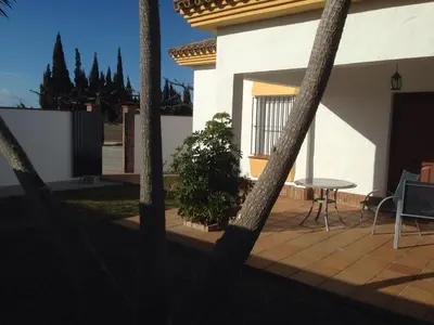 a patio with a table and chairs in front of a house at Chalet Rancapinos en Rocheviejo CONIL in Cádiz