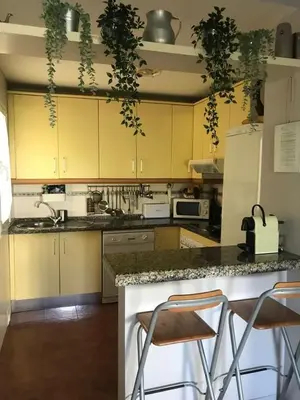 a kitchen with yellow cabinets and two bar stools at EXCLUSIVE APARTMENT 3 HAB Wifi in Rota