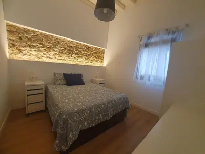 a small bedroom with a bed and a window at Casa Parque Genovés junto a la playa in Cádiz