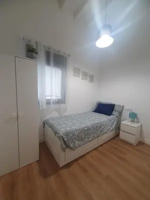 a white bedroom with a bed and a window at Casa Parque Genovés junto a la playa in Cádiz