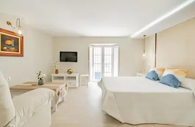 a white bedroom with a large bed and a couch at Loft Casa del Duque in Arcos de la Frontera