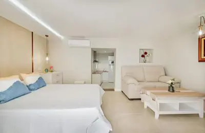 a white bedroom with a large bed and a couch at Loft Casa del Duque in Arcos de la Frontera