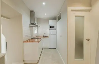 a white kitchen with a sink and a refrigerator at Loft Casa del Duque in Arcos de la Frontera