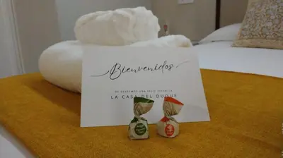 a sign on a table with two little figurines on a bed at Loft Casa del Duque in Arcos de la Frontera
