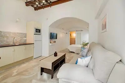 a living room with a white couch and a kitchen at La Cueva del Corregidor in Arcos de la Frontera