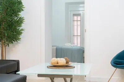 a living room with a glass table and a blue couch at Falla Loft & Beach in Cádiz