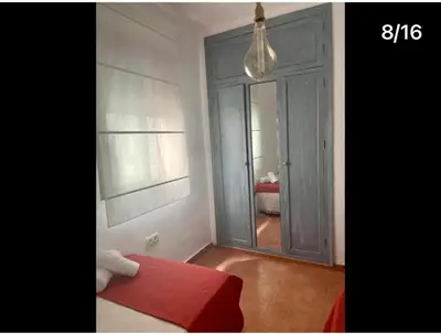 a room with a bed and a window with a mirror at Apartamento Reina Mercedes in Chipiona