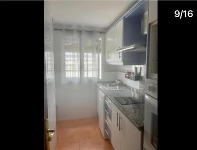 a kitchen with white cabinets and a sink and a window at Apartamento Reina Mercedes in Chipiona