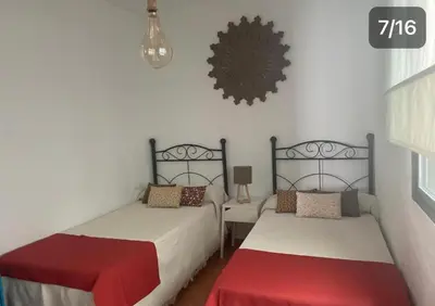 a bedroom with two beds and a clock on the wall at Apartamento Reina Mercedes in Chipiona