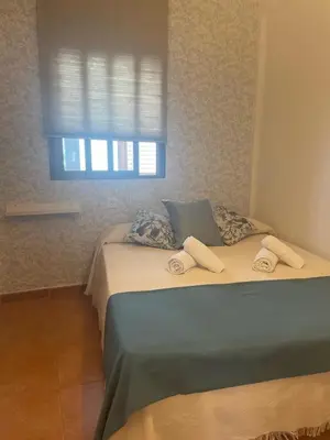 a bed in a room with a window with towels on it at Apartamento Reina Mercedes in Chipiona