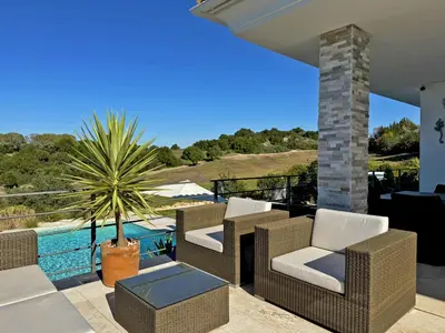 a patio with chairs and a palm tree and a pool at Villa Montecastillo - Ole Solutions in Jerez de la Frontera