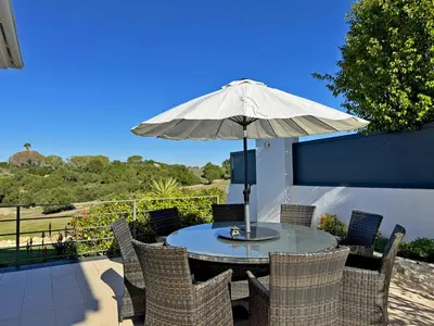 a table and chairs with an umbrella on a patio at Villa Montecastillo - Ole Solutions in Jerez de la Frontera