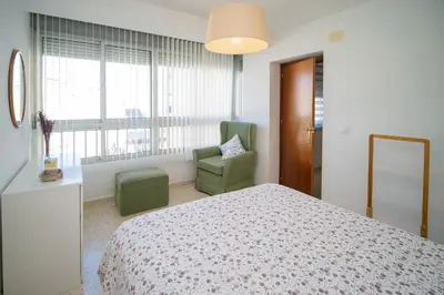 a bedroom with a bed and a chair and a window at Piso Barrameda in Sanlúcar de Barrameda