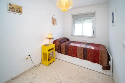 a bedroom with a bed and a yellow table with a lamp at Piso Barrameda in Sanlúcar de Barrameda