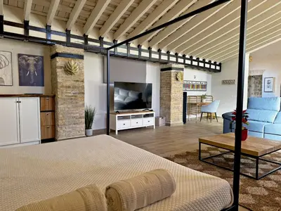 a bedroom with a large bed and a living room at La Bodeguita - Ole Solutions in Jerez de la Frontera