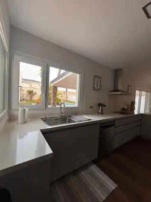 a large kitchen with a sink and two windows at La caprichosa in Chiclana de la Frontera