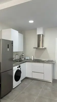 a kitchen with white cabinets and a stainless steel refrigerator at Lacana 2 in Chiclana de la Frontera