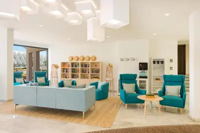 a living room with blue chairs and a couch at Iberostar Waves Royal Andalus in Chiclana de la Frontera