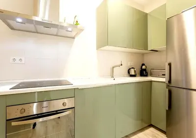 a kitchen with green cabinets and a stainless steel refrigerator at precioso piso en playa caleta in Cádiz