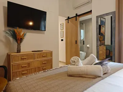 a bedroom with a bed with a tv on the wall at Le Charme Little Apartments in Cádiz