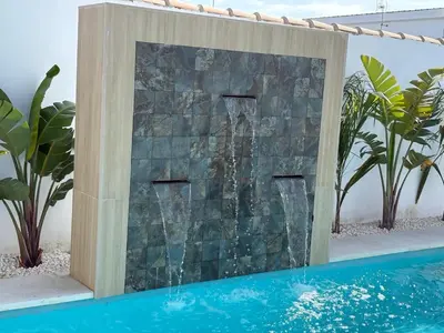 a waterfall in a stone wall next to a swimming pool at GUACA 2 in Cádiz