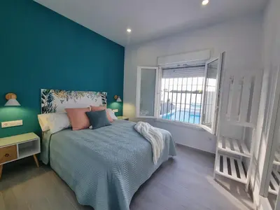 a bedroom with a bed with blue walls and a window at Casa Calma in Conil de la Frontera