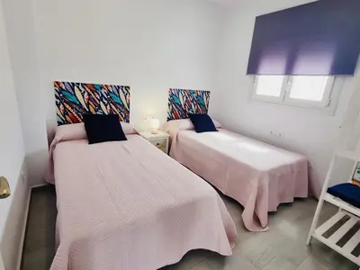 a room with two beds with pink sheets at Casa Calma in Conil de la Frontera