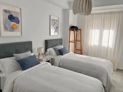 two beds in a bedroom with white and blue at Victoria Centro 34 in Puerto Real