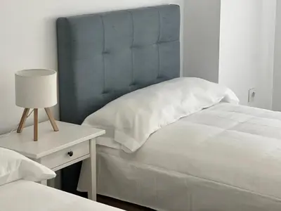 a bed with a blue headboard and a table with a lamp at Victoria Centro 34 in Puerto Real