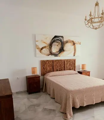 a bedroom with a bed and a painting on the wall at Casa de los Patios in Sanlúcar de Barrameda