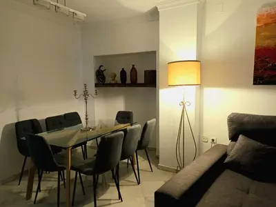 a dining room with a table and chairs and a lamp at Casa de los Patios in Sanlúcar de Barrameda