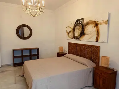 a bedroom with a bed and a mirror and a chandelier at Casa de los Patios in Sanlúcar de Barrameda