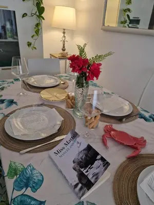 a table with plates and red flowers and a book at Next to piletas 67 Sanlucar de Barrameda in Sanlúcar de Barrameda