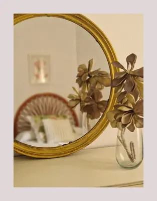 a mirror on a table with a vase with flowers at Next to piletas 67 Sanlucar de Barrameda in Sanlúcar de Barrameda
