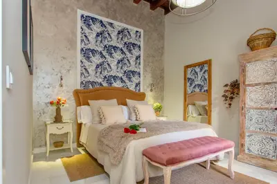 a bedroom with a large bed with a pink bench at Wehostcostaluz Le Petit Palace Catedral con parking gratuito in Jerez de la Frontera