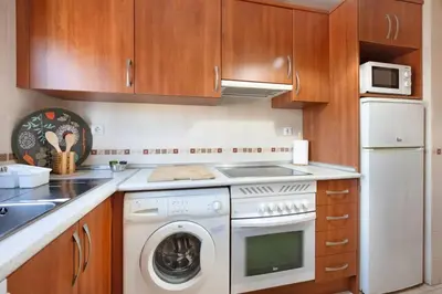a kitchen with a washer and dryer and wooden cabinets at Golden Sands Apartment - Chiclana de la frontera in Novo Sancti Petri